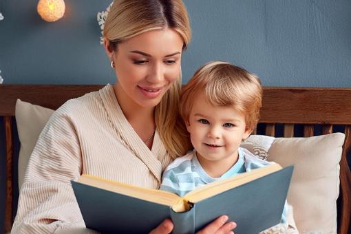 Eine Mutter liest ihrem Kind im Bett aus einem Buch vor