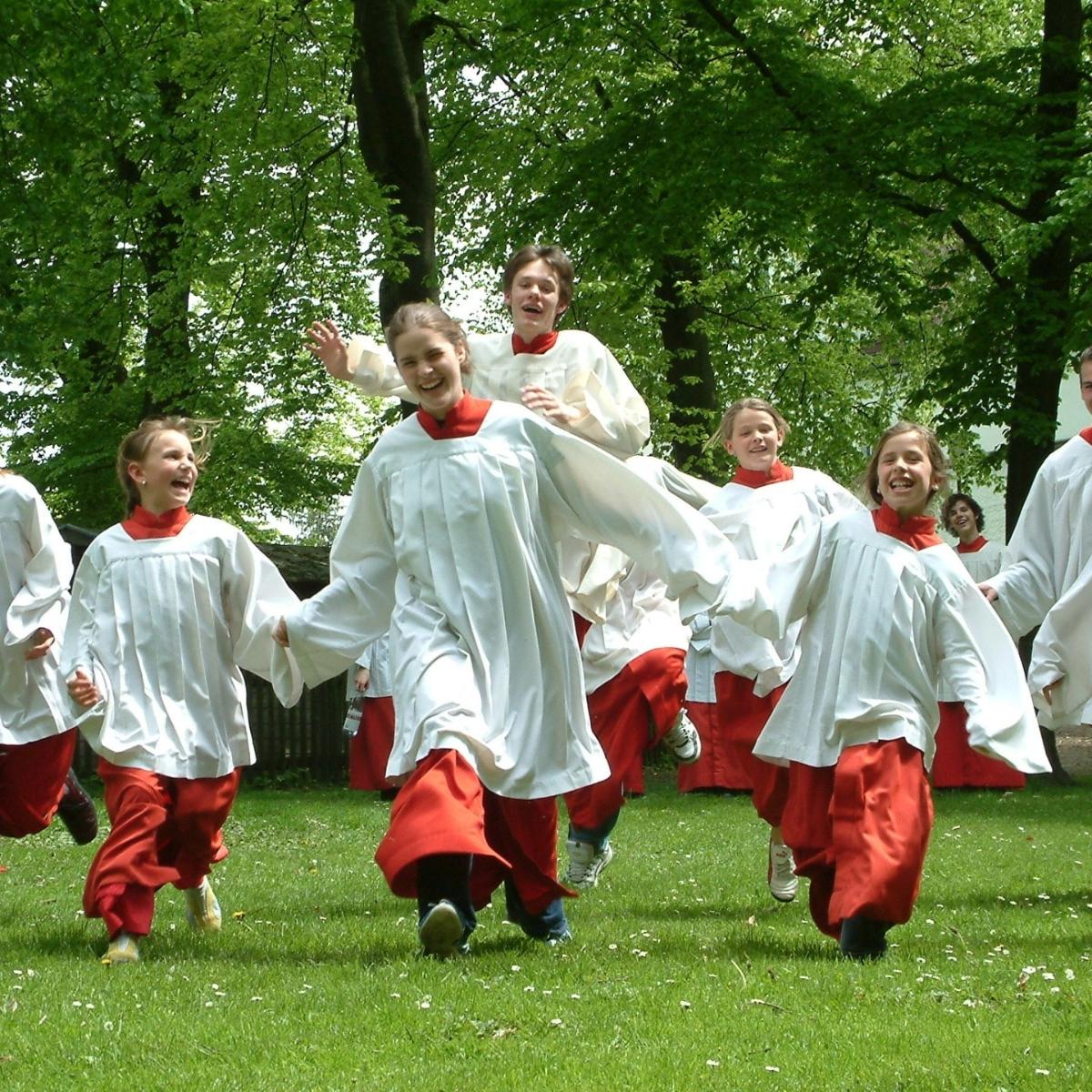 eine Gruppe Messdiener läuft über eine Wiese